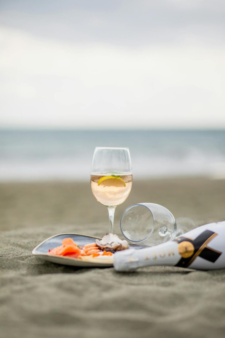 Close-up of wine and snacks on a peaceful beach, capturing luxury and relaxation.